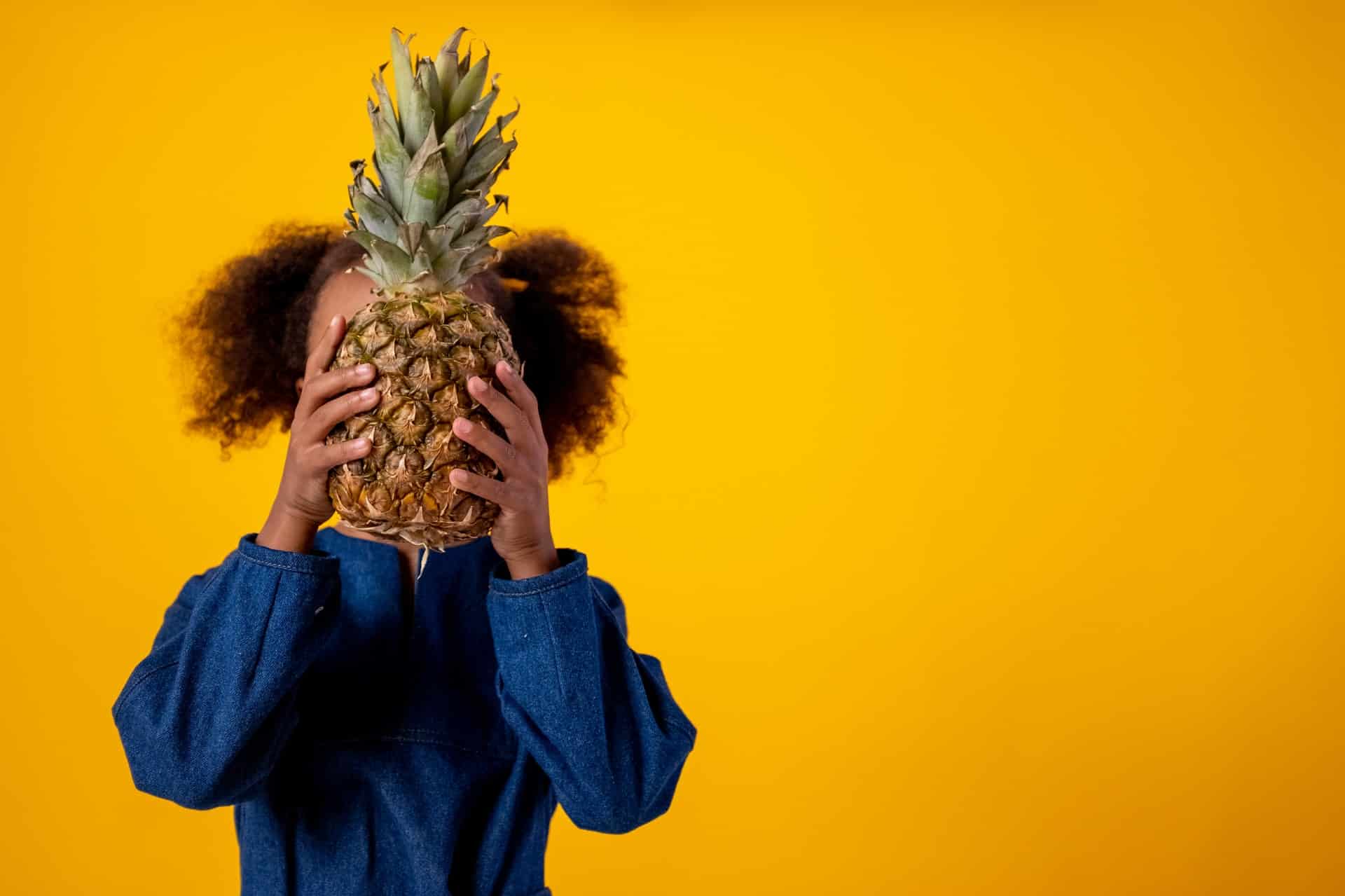child hiding behind a pineapple